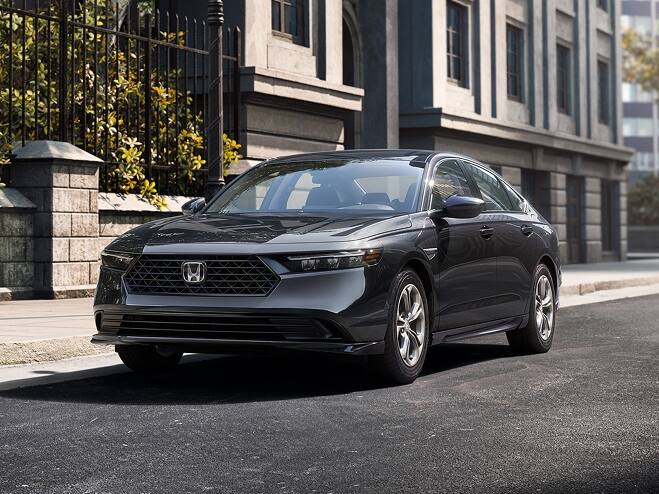 2026 Honda Accord in Meteorite Gray Metallic parked on the street next to a building and a city park with trees.