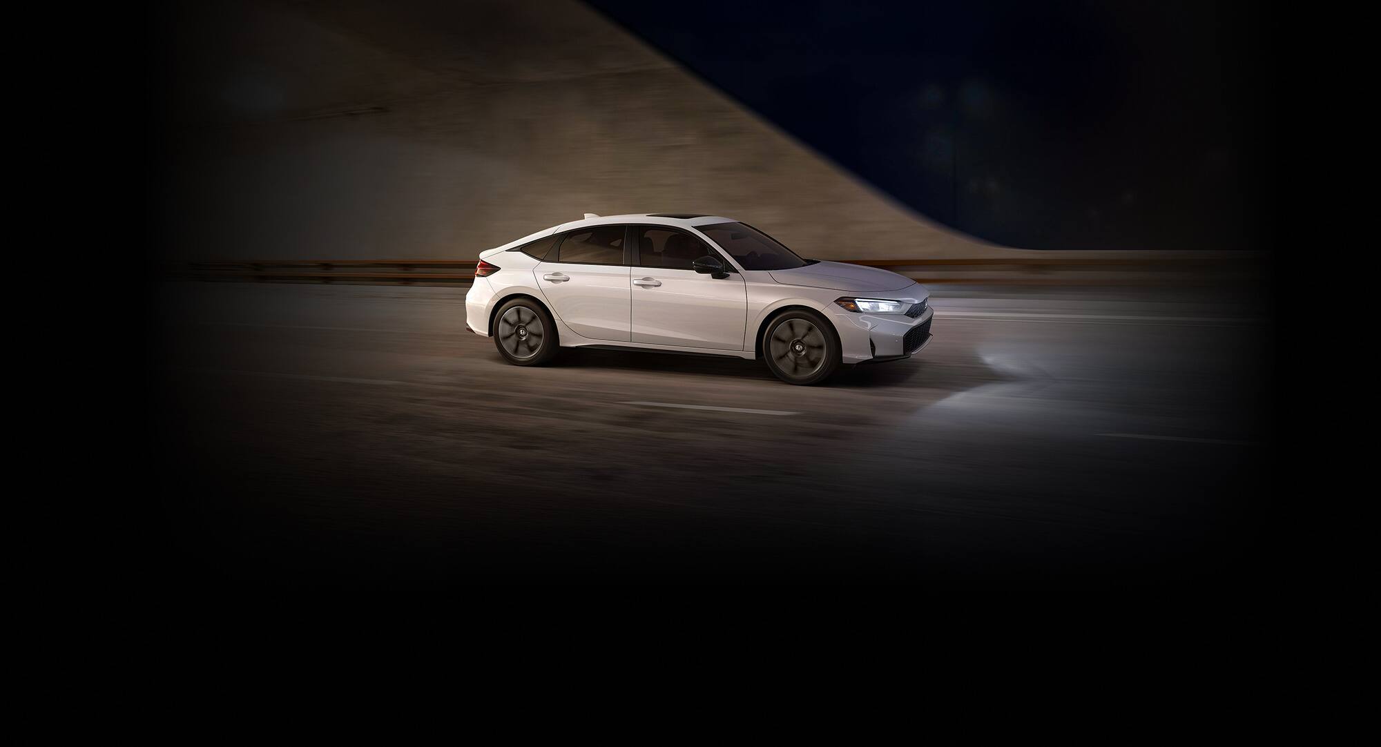 2027 Honda Civic Hatchback Touring Hybrid in Platinum White Pearl profile driving through a tunnel (Compact Hatchback).